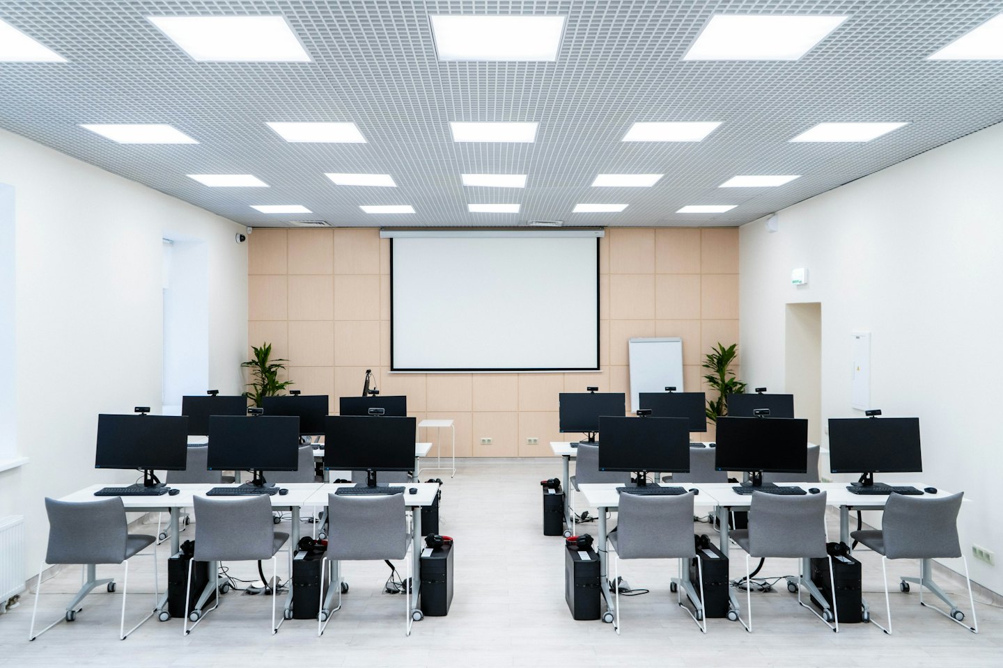 Modern computer lab with rows of computers and chairs.