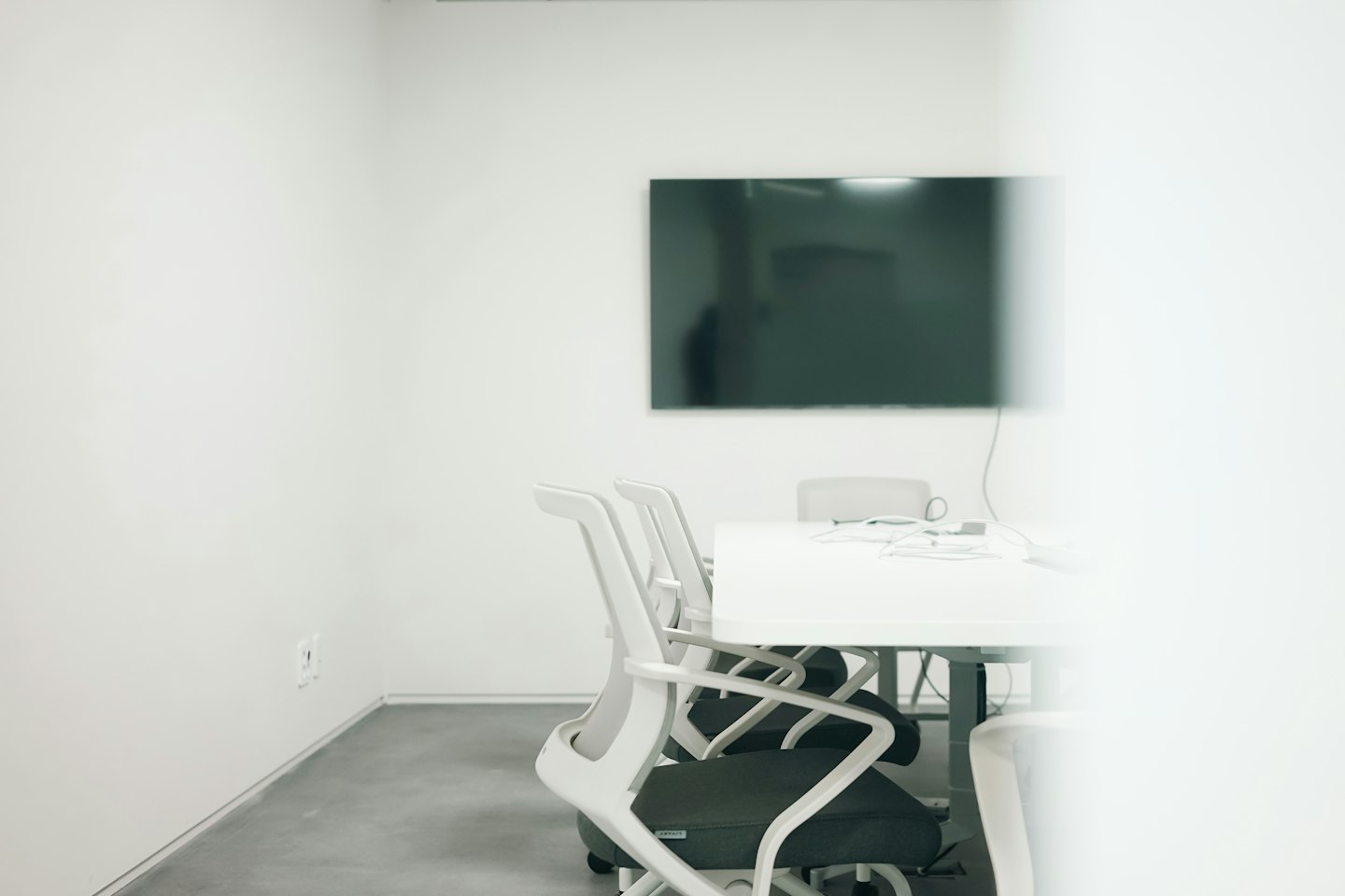 Modern meeting room with a conference table and wall monitor.